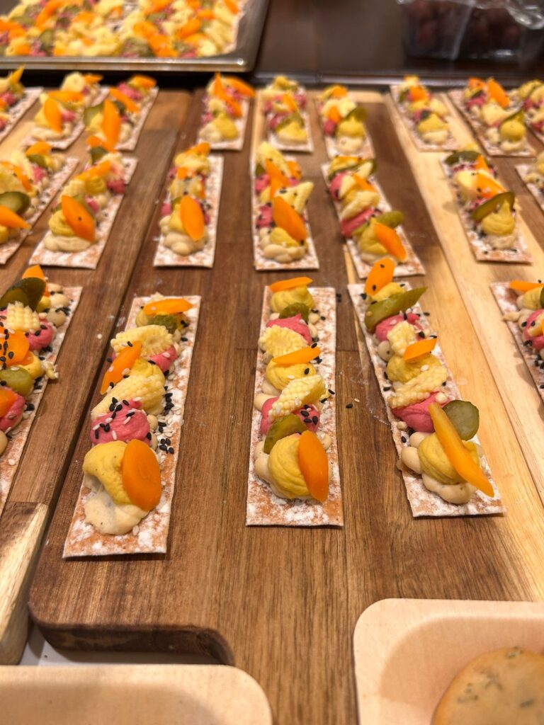 Tostas de hummus con verduras encurtidas sobre tabla de madera, catering en Palma